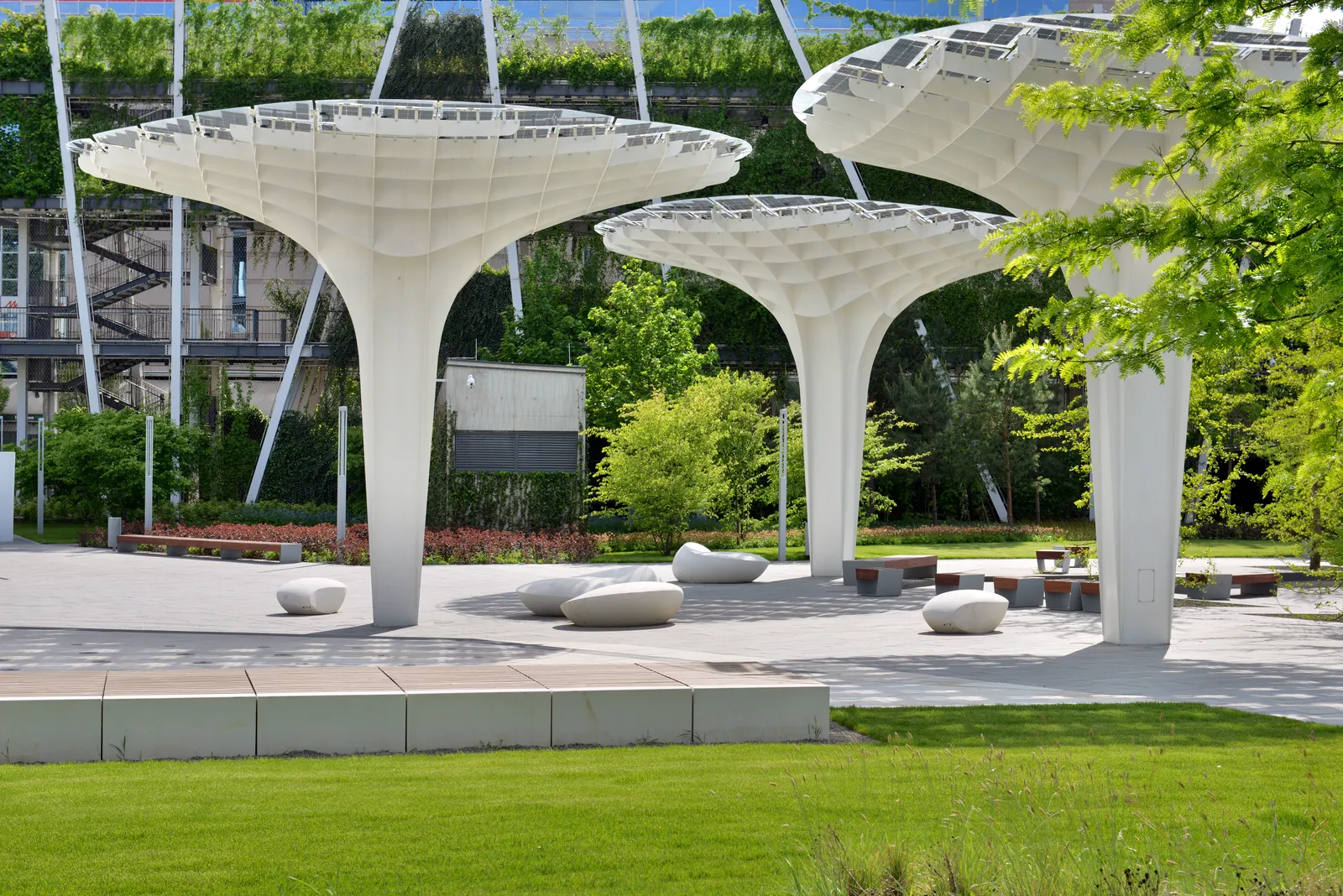 A Millenáris Széllkapu Park jellegzetes gomba alakú napelemes árnyékolói kőpadokkal és zöldfelülettel