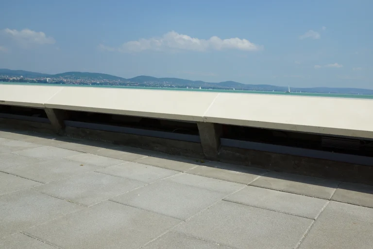 Kilátás a Balatonra és a távoli hegyekre a tihanyi közforgalmi kikötő korlátja fölött